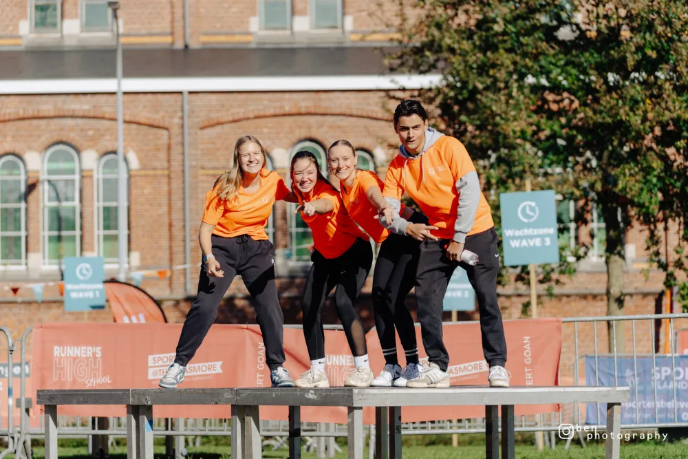 Vier studenten in oranje shirts juichen op het podium