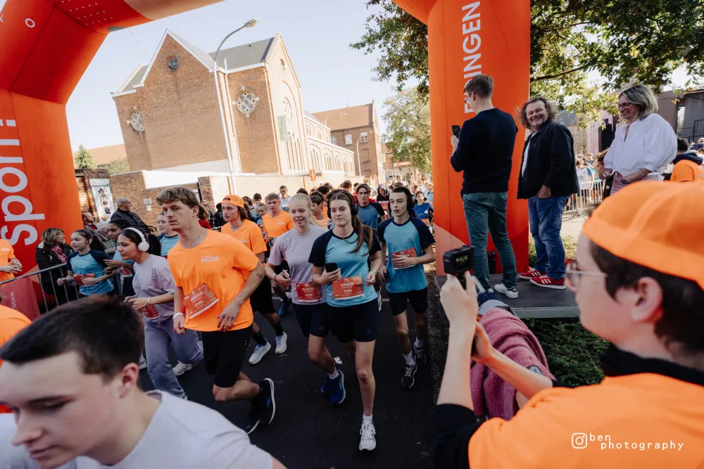 Leerlingen lopen onder de oranje startboog